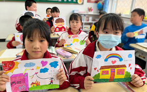 Classroom of chinese students holding thank-you drawings