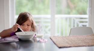 Small child eating cereal at a table