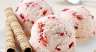 pink strawberry ice cream with red strawberries on a plate with wafer straws